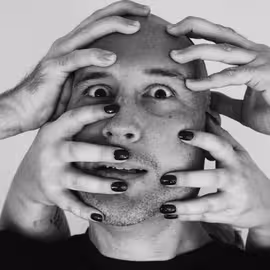 Publicity photo of Macbeth's face accosted by creepily grasping hands that reach for his eyes and mouth.