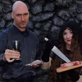Publicity photo of Macbeth and Lady Macbeth serving a macabre banquet within their castle.