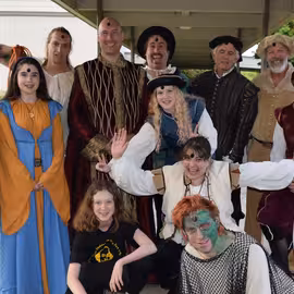 The cast and crew for the play The Tempest in costume gathered behind the performance venue before a show.