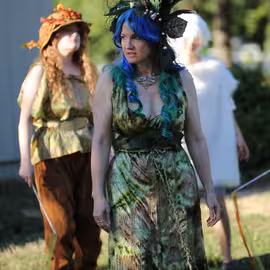 The fairy queen Titania glares furiously as her fairy retinue watches from a distance in the play A Midsummer Night's Dream.